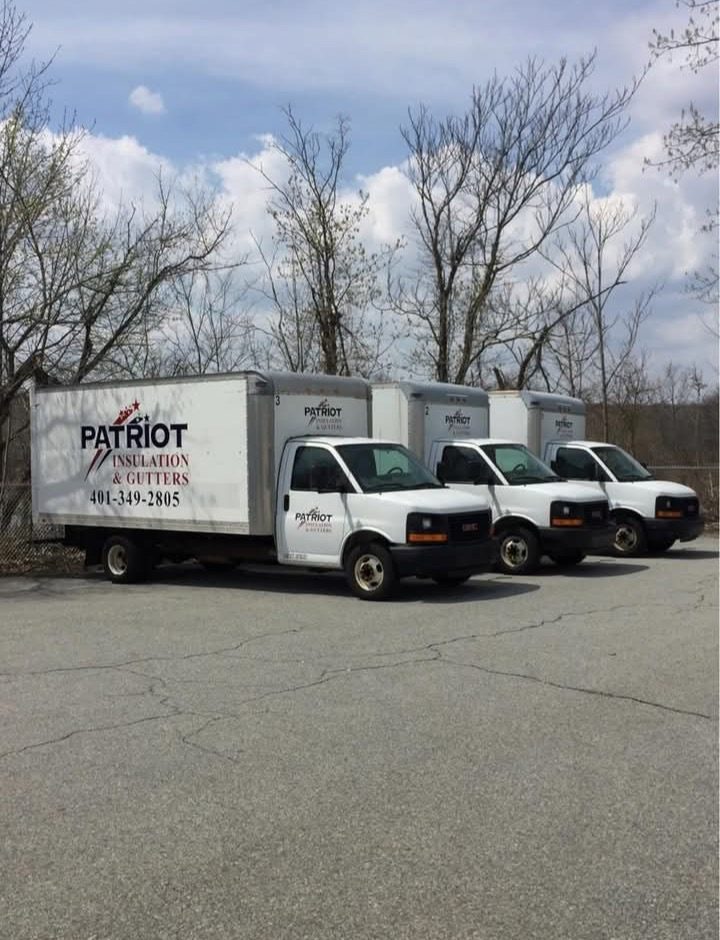 Three numbered Patriot Insulation and Gutters box trucks parked in the company yard