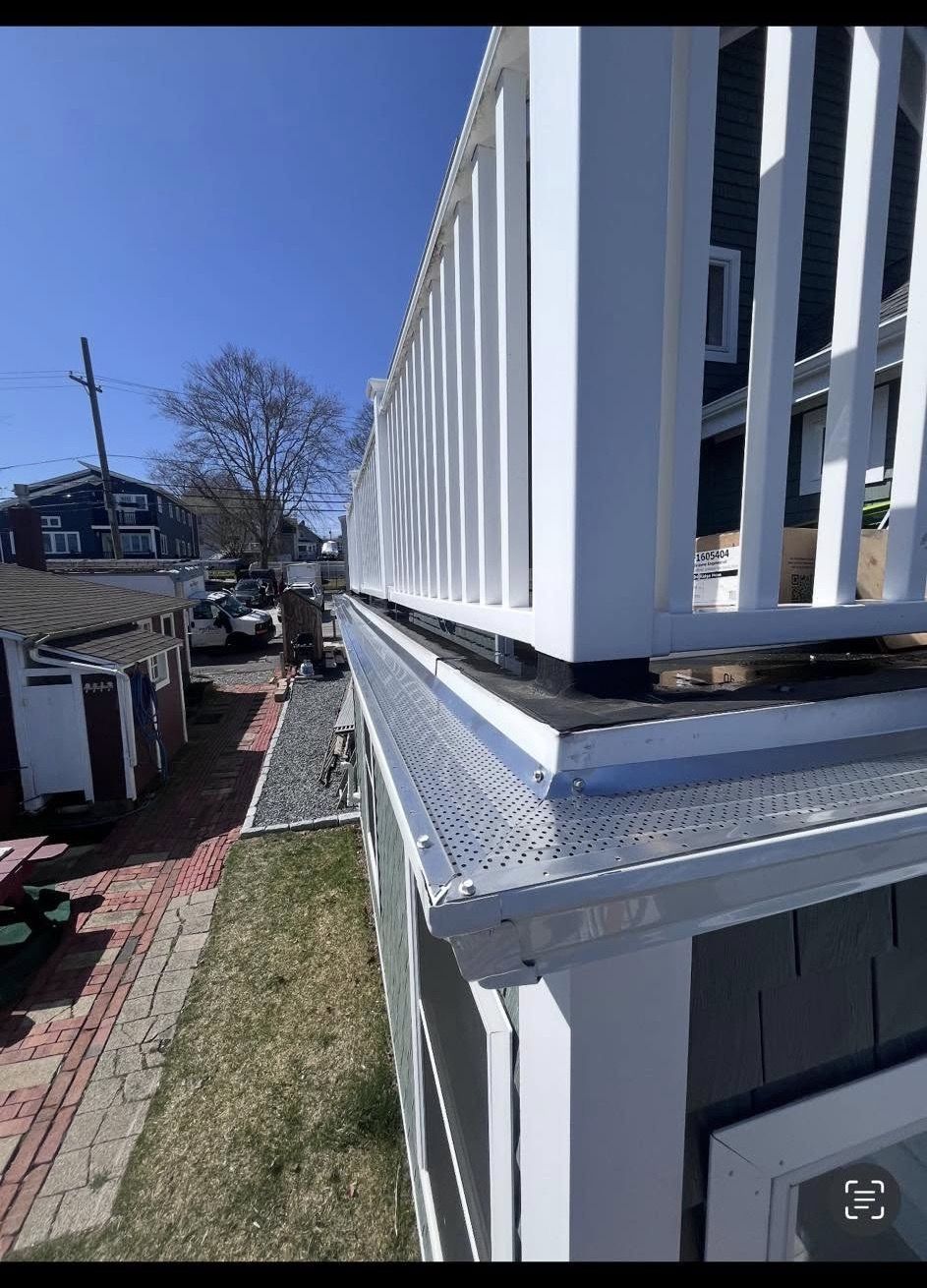 Perforated aluminum gutter guard installed over a white gutter on a New England home